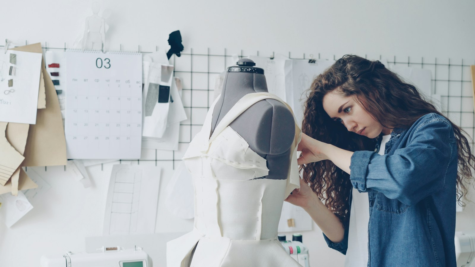 Placeholder: seamstress pinning a garment on a dress form